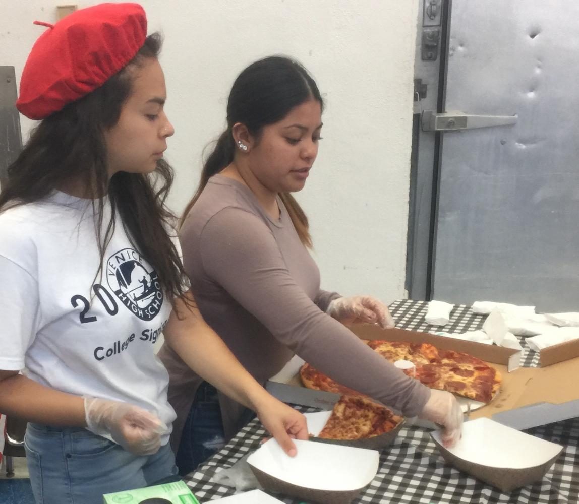 Venice High ASB students Tania Paz and Mona Viera serve pizza during the luncheon. 