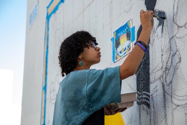 Vision of the future: Senior Jeannie Fischer helps paint a new mural between the West and Main Buildings during the final days before graduation. The mural is a collaboration between Venice's M.E.Ch.A chapter and Art Factory, a club dedicated to art-making. The mural centers on silhouettes with traditional Latin American clothing and a backdrop of a sunset on Venice Beach---adorned with palm trees, cempasúchil (also known as marigolds), and monarch butterflies.