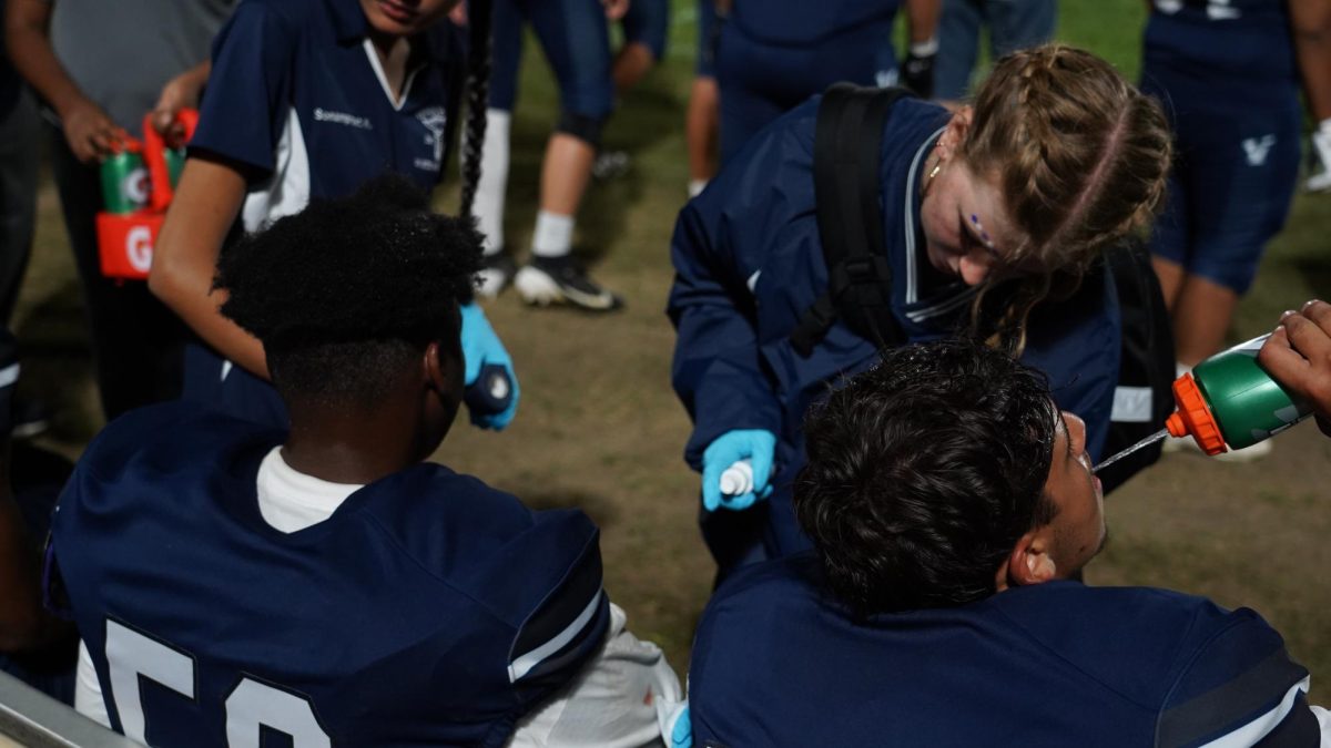 On the job: Junior Lumi Cushing cleans blood off of senior George Vallejo with hydrogen peroxide at a football game against Harvard-Westlake September 5.
